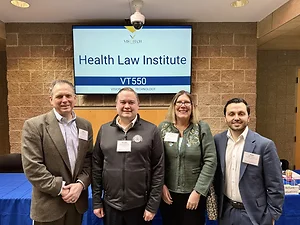 Group of attorneys in front of tv screen smiling at camera